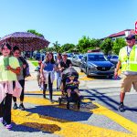 A group of people walking across the street with the help of a crossing guard