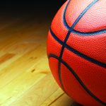 A large basketball in the shadow of the court